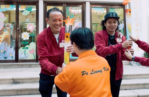 翁金驊先生（左）、阿感（右）分別從保良局服務使用者及管理層手上接過火炬，寓意將共融訊息傳遍保良局屬下社服單位。